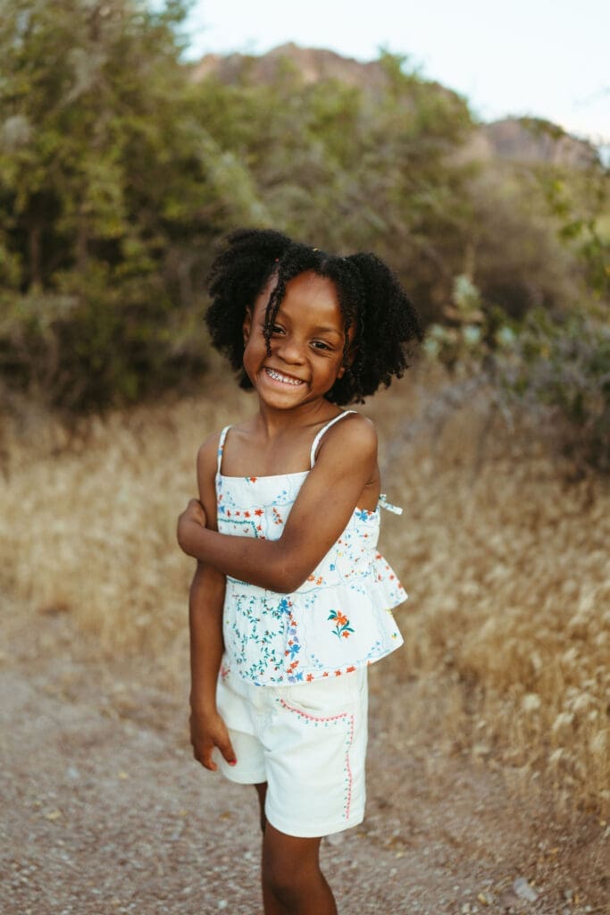 Smiling young girl posing during an outdoor family photo session in Apache Junction