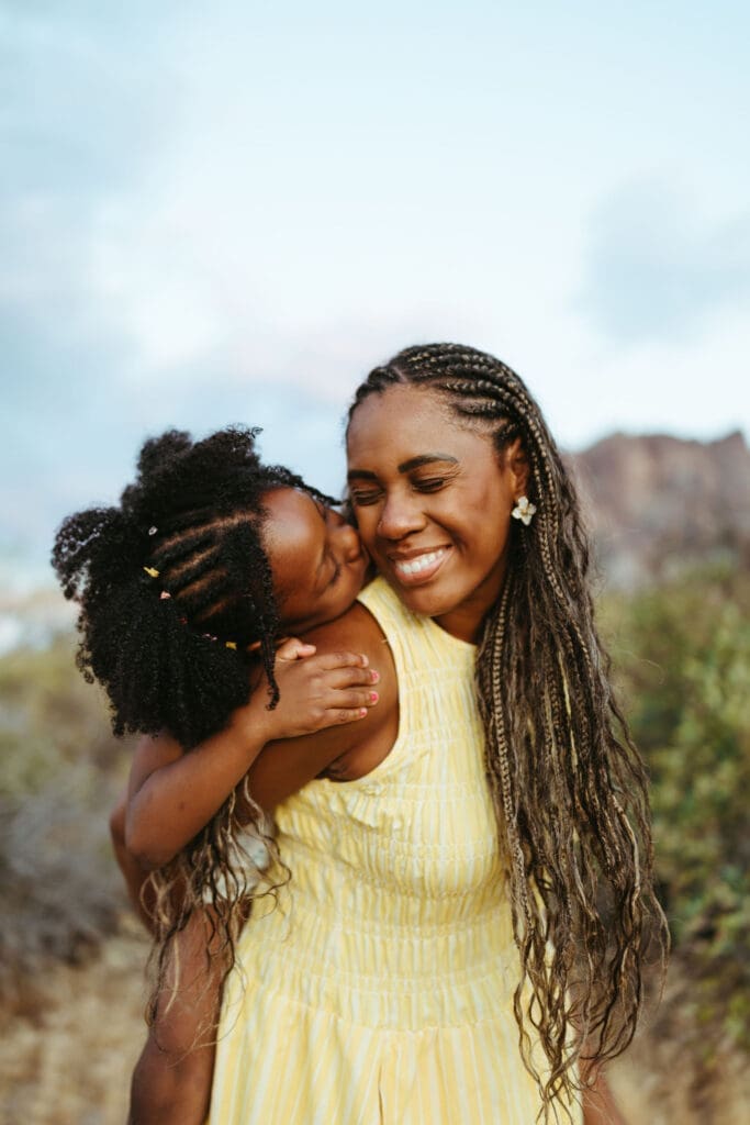 Mother giving her daughter a piggyback ride during a family session with the Superstition Mountains in the background