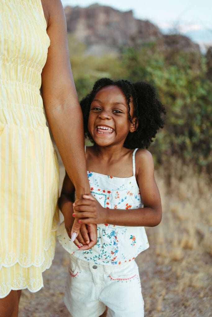 Smiling young girl holding her mother's hand during an outdoor family photo session