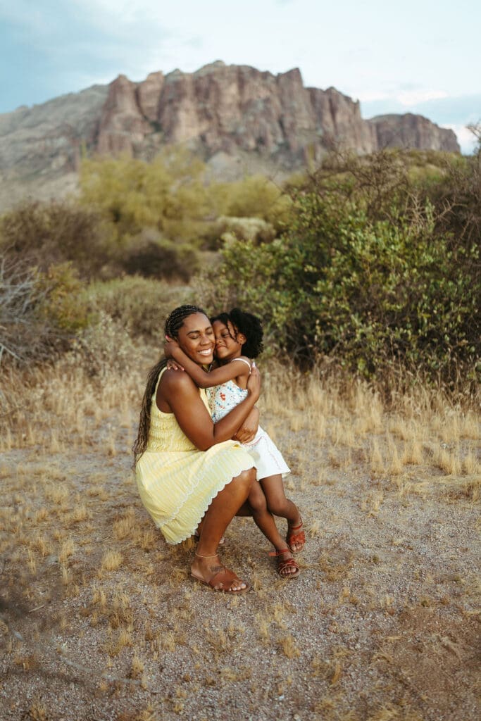 Mother hugging her daughter with the Superstition Mountains in the background during a family session