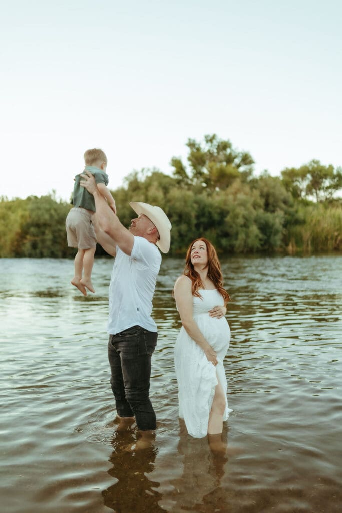 Pregnant mother and family standing together in the Salt River during golden hour in Mesa, Arizona.