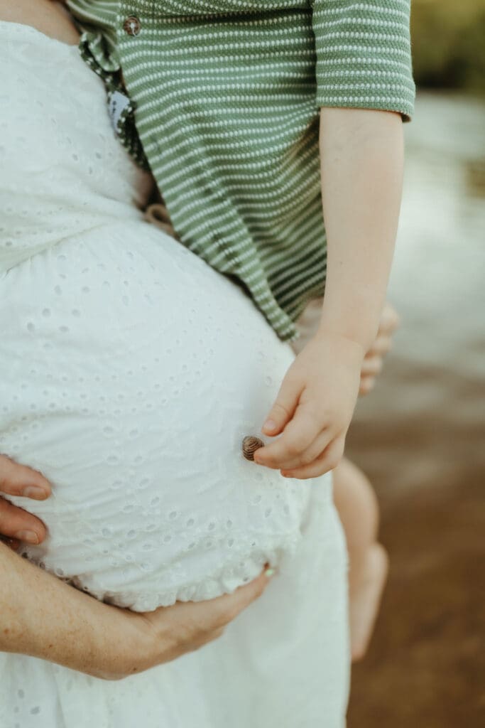 Close-up maternity detail of a toddler holding his mother's pregnant belly during a Mesa maternity session.