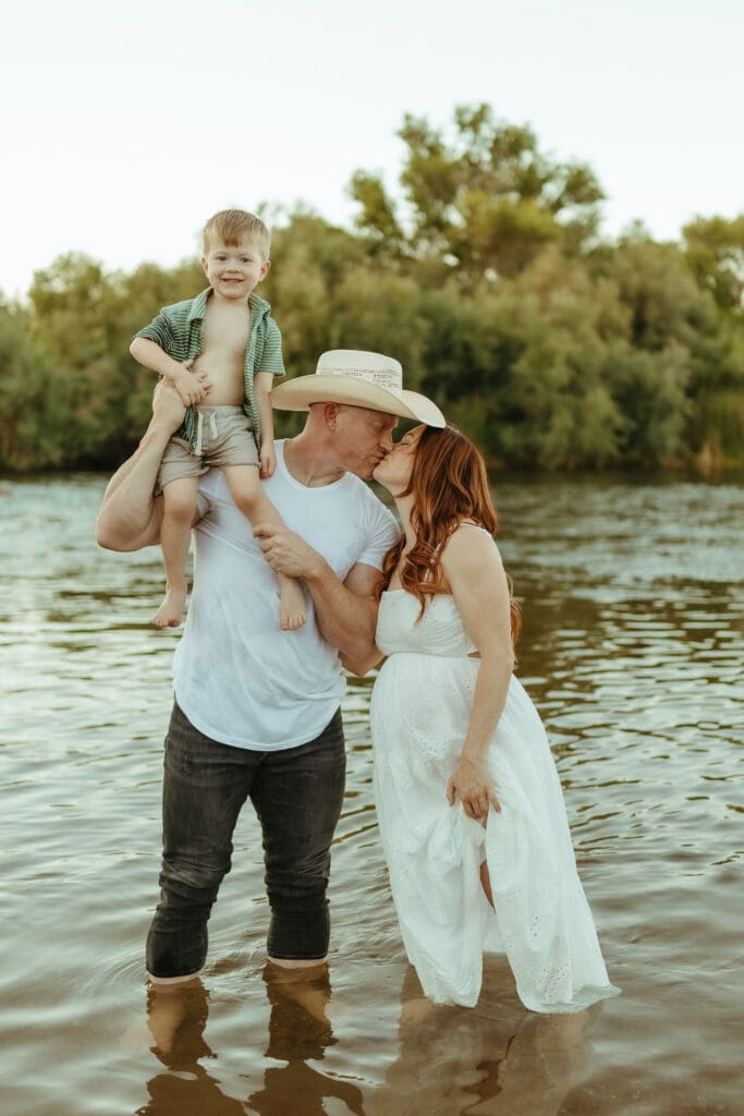 Pregnant mother and family standing together in the Salt River during golden hour in Mesa, Arizona.