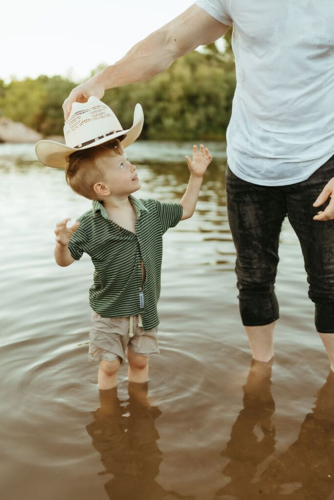 Toddler wearing a cowboy hat while playing in the Salt River during a family maternity session in Mesa, Arizona.