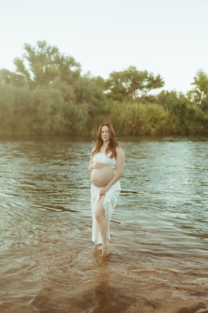 Pregnant mother standing barefoot in the Salt River during a sunset maternity photography session near Gilbert and Mesa.