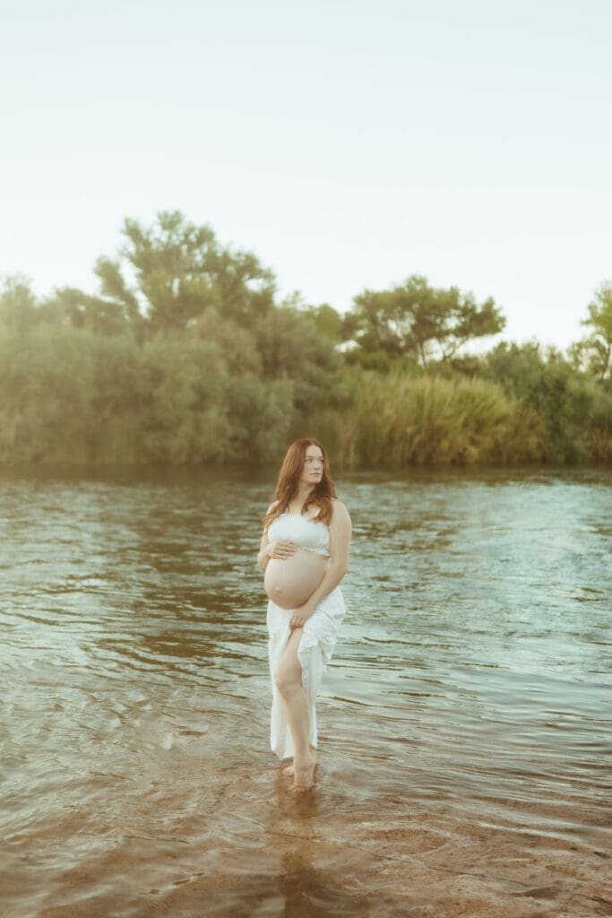 Expecting mother standing in the Salt River during golden hour at Phon D Sutton Recreation Area in Mesa, Arizona.