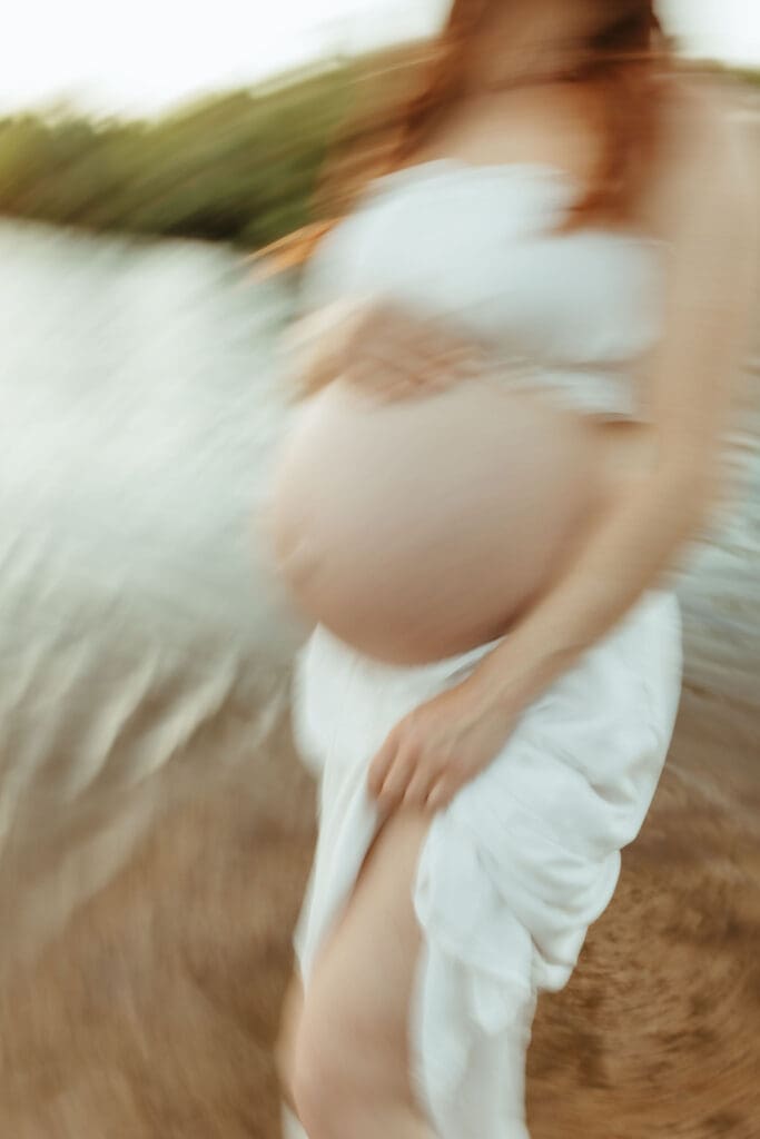 Expecting mother standing in the Salt River surrounded by lush greenery during a Mesa maternity session.