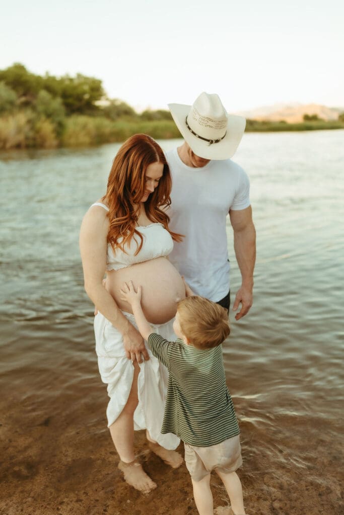 Family admiring mom's baby bump during a Salt River maternity photography session near Phoenix, Arizona.