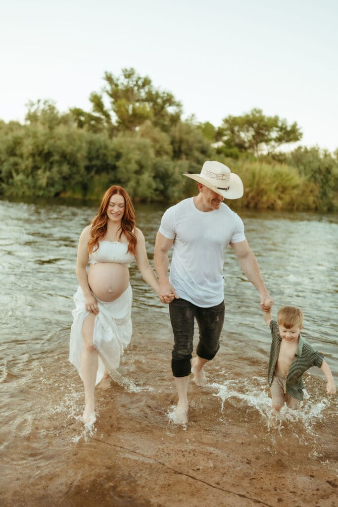 Family walking through the Salt River during a sunset maternity session at Phon D Sutton Recreation Area.