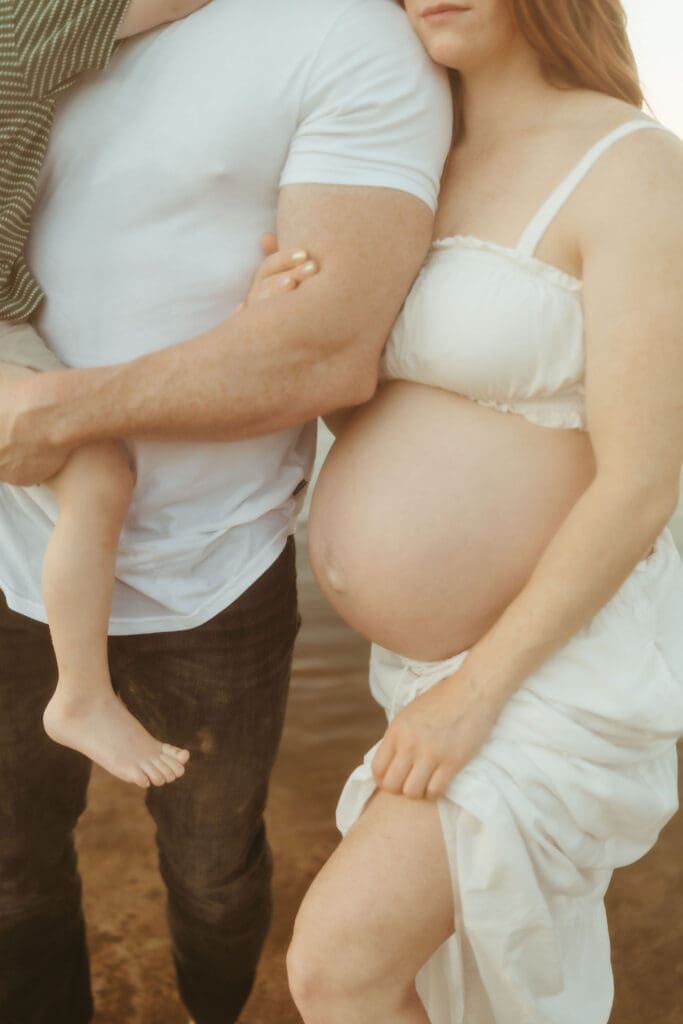 Artistic close-up of expecting parents embracing during a Salt River maternity photography session in Arizona.