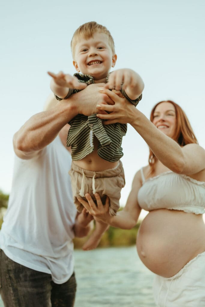 Father lifting his son during an outdoor family maternity session at the Salt River in Mesa.