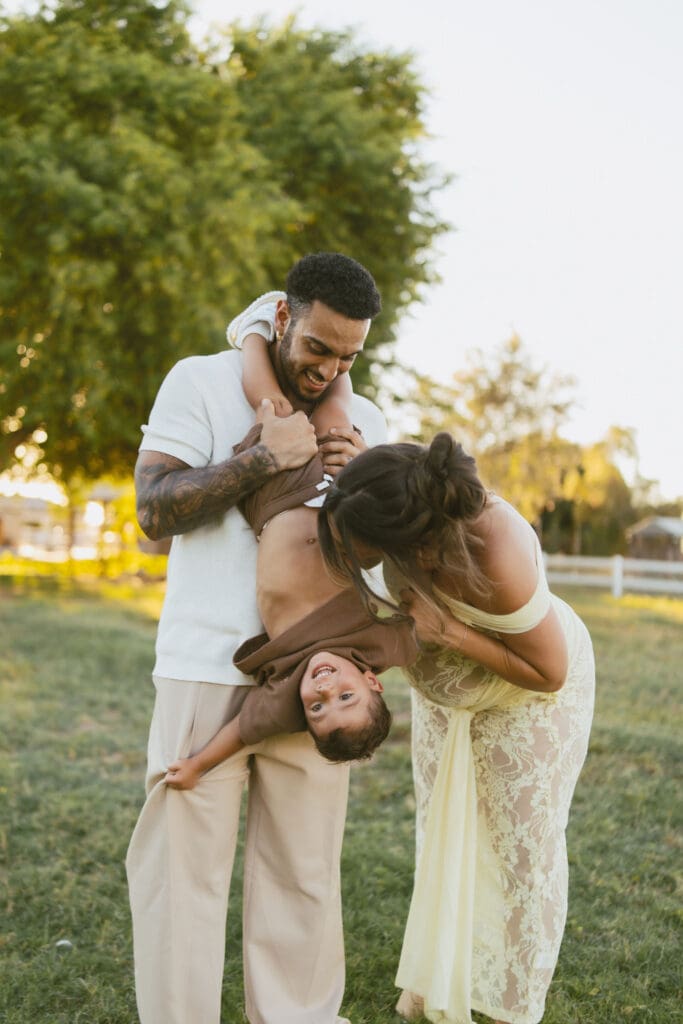 Parents playing with their toddler during a relaxed outdoor maternity photography session in Queen Creek, Arizona.