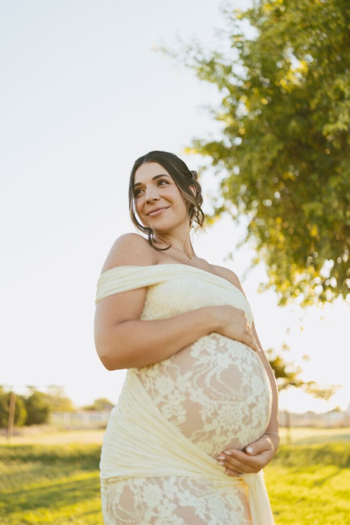 Pregnant mother smiling during a golden hour maternity portrait in Gilbert, Arizona.