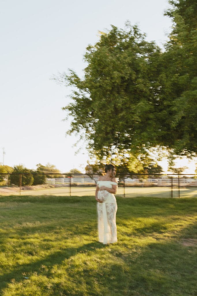 Pregnant mother standing in a grassy field during a sunset maternity session in Gilbert, Arizona.