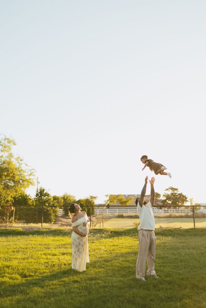 Father lifting his toddler into the air during a family maternity session at Patch of Paradise AZ.
