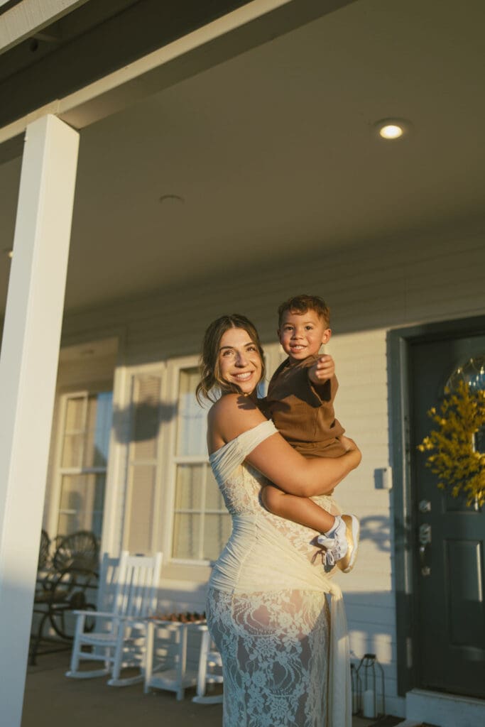 Mother holding her toddler on the front porch during a maternity session at Patch of Paradise AZ in Gilbert.