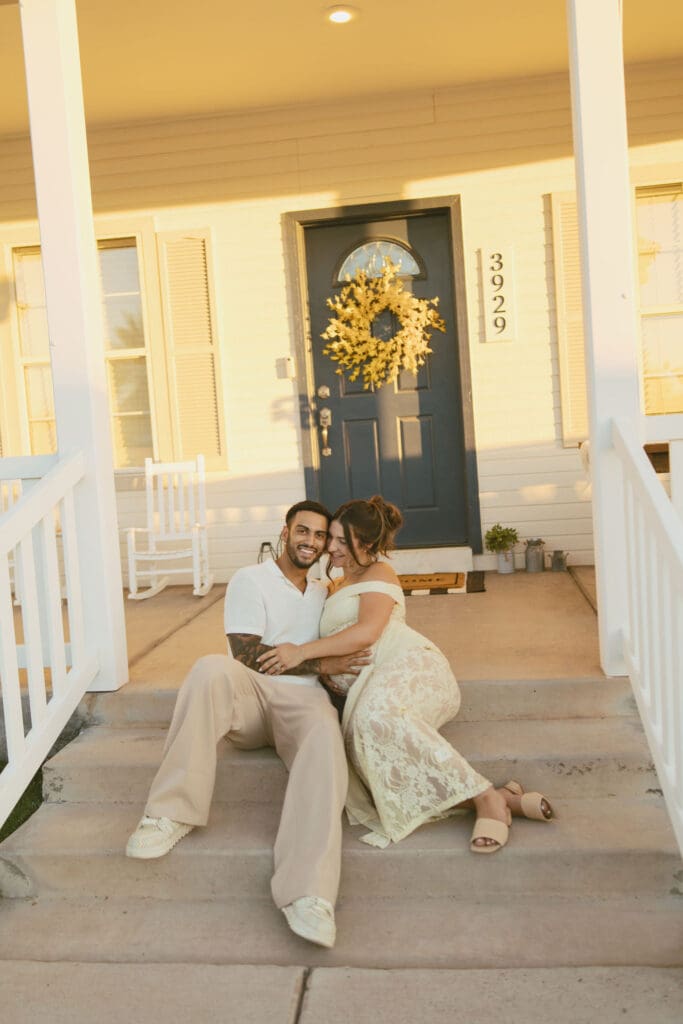Expecting parents sitting on the front porch with their toddler during a relaxed family maternity session near Queen Creek.