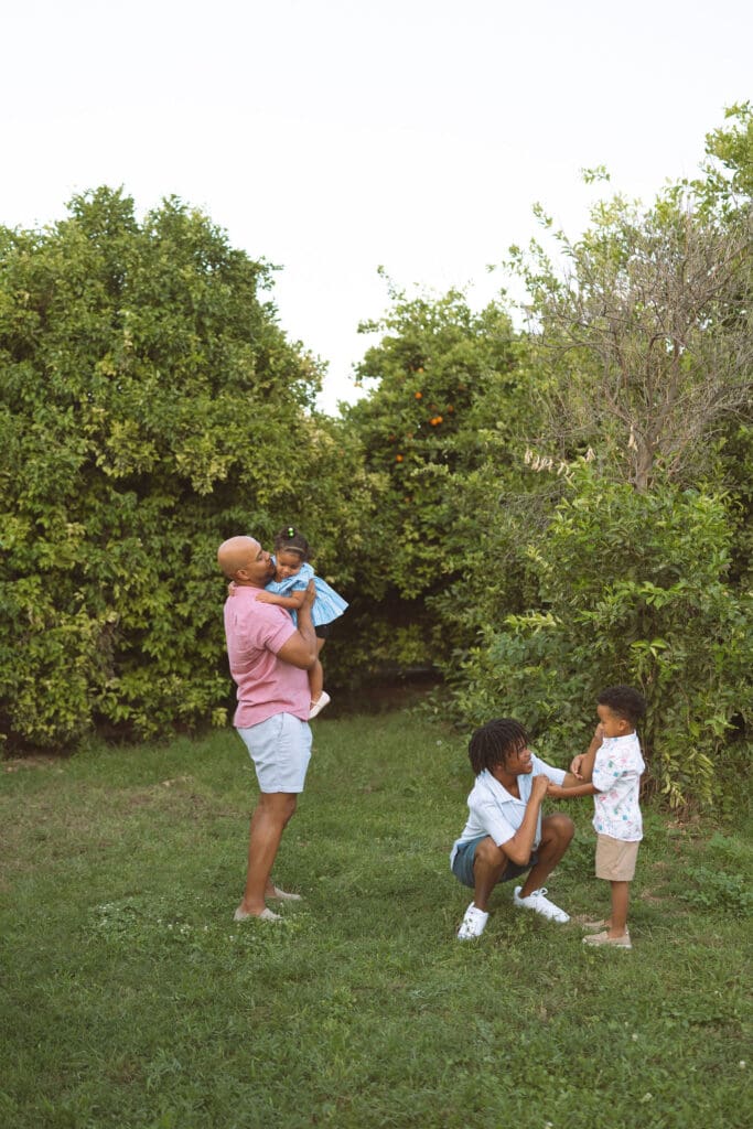 Family enjoying playful moments in a green citrus orchard during a Queen Creek family photography session.