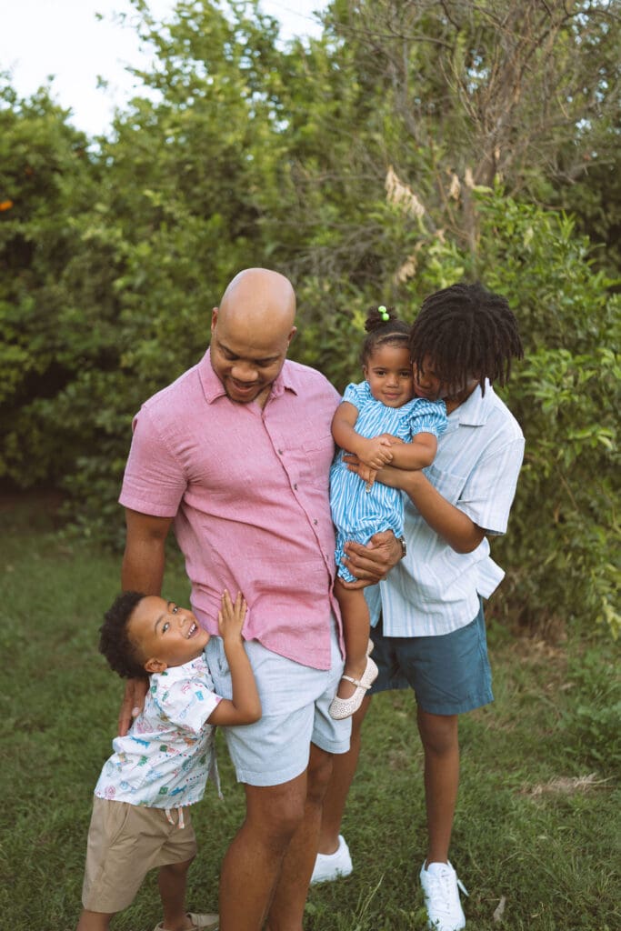 Young siblings hugging their father during an outdoor family photo session near Gilbert and Queen Creek.