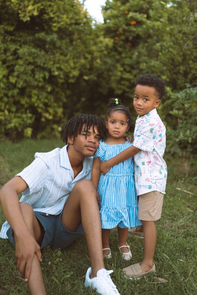 Older brother posing with his younger siblings during an outdoor family session in Queen Creek, Arizona.