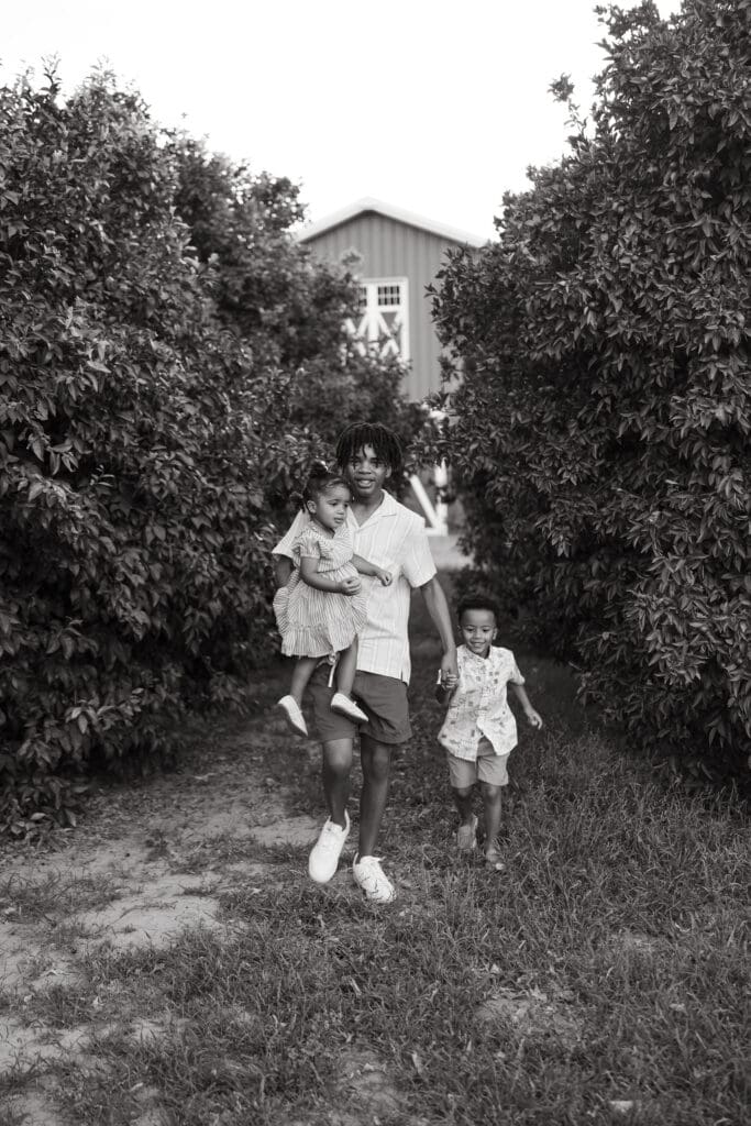 Black and white family portrait walking through the citrus orchard at Hagen Farms in Queen Creek.