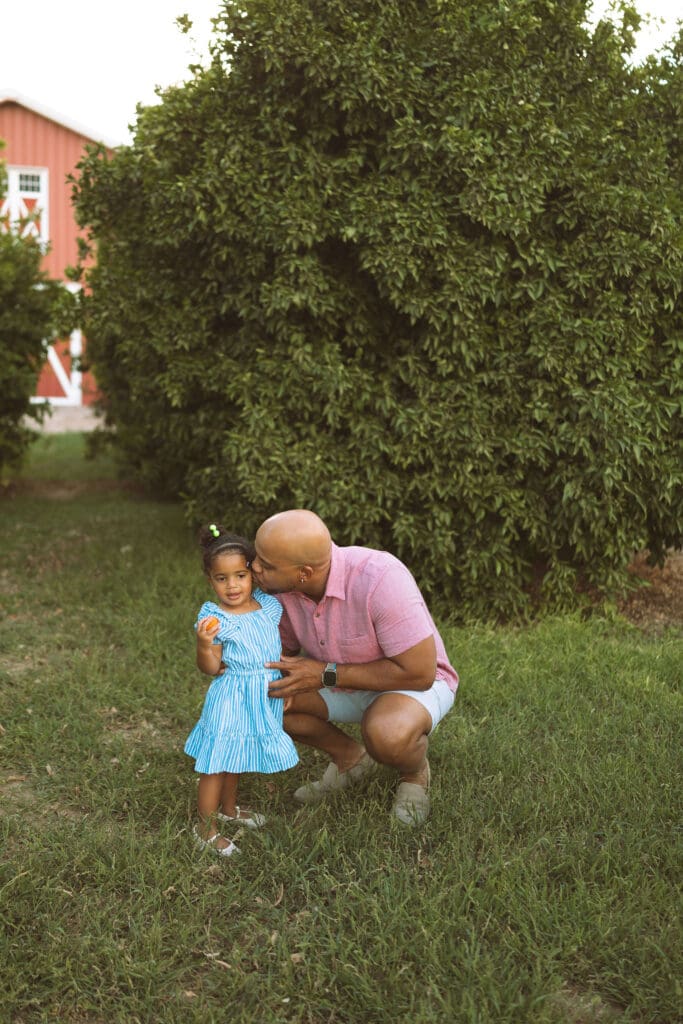 Father hugging his daughter in a lush citrus orchard during a Queen Creek family photo session.