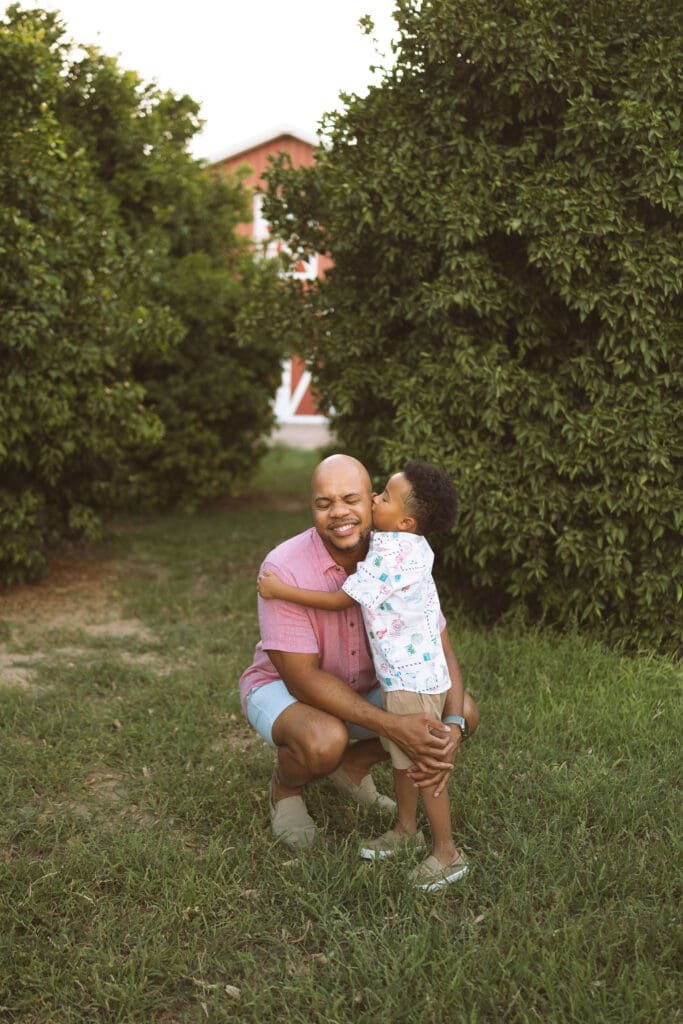 Father hugging his son during a joyful outdoor family photography session at Hagen Farms in Queen Creek.