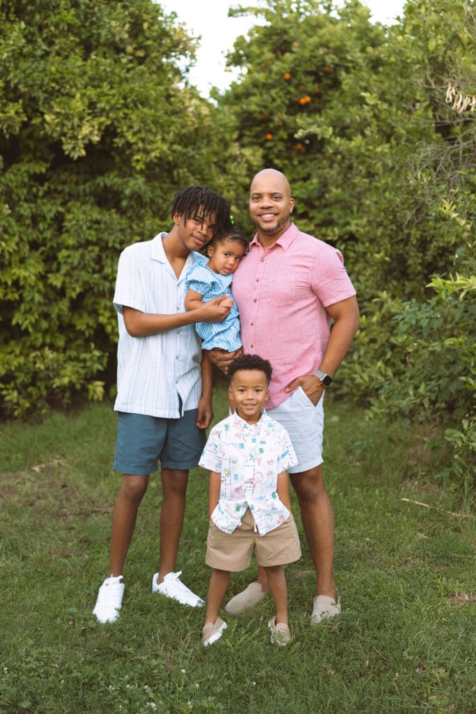 Family of four posing together in a green citrus orchard at Hagen Farms in Queen Creek, Arizona.
