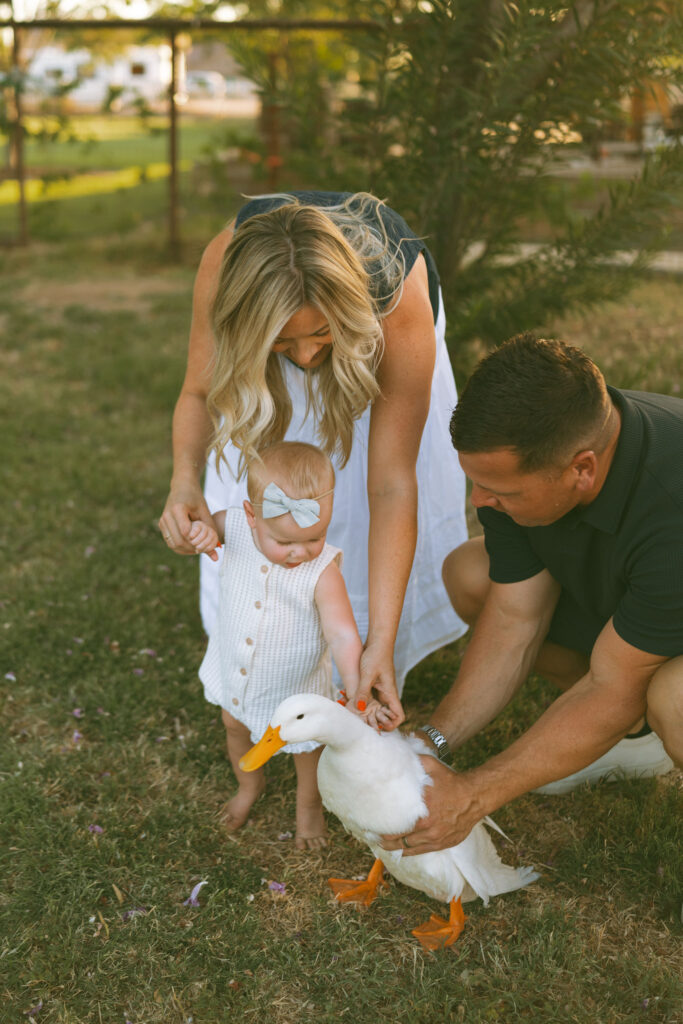 Mom smiling while holding a white duck during a relaxed outdoor family photo session in Gilbert, Arizona.