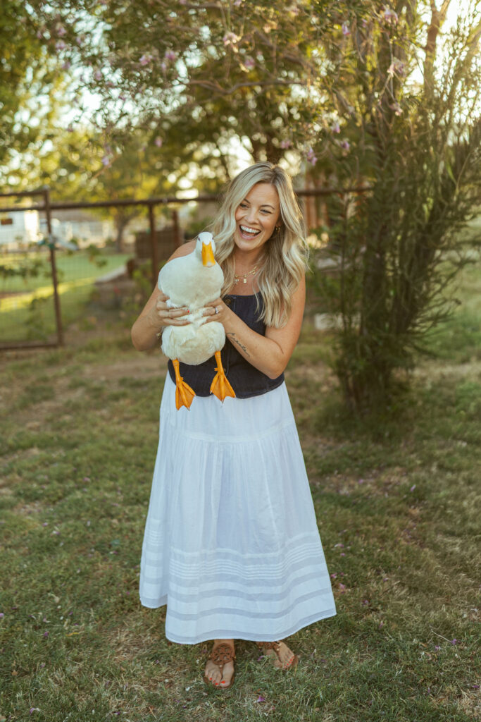 Mom smiling while holding a white duck during a relaxed outdoor family photo session in Gilbert, Arizona.
