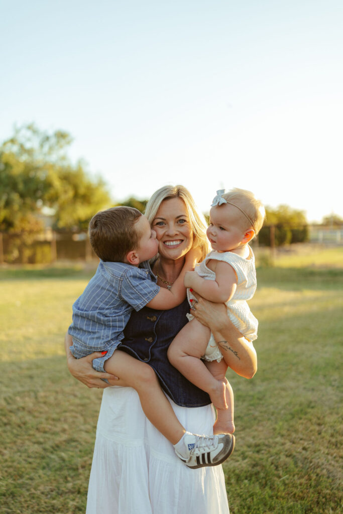 Mother holding her two young children during a warm golden hour family photography session in Gilbert.