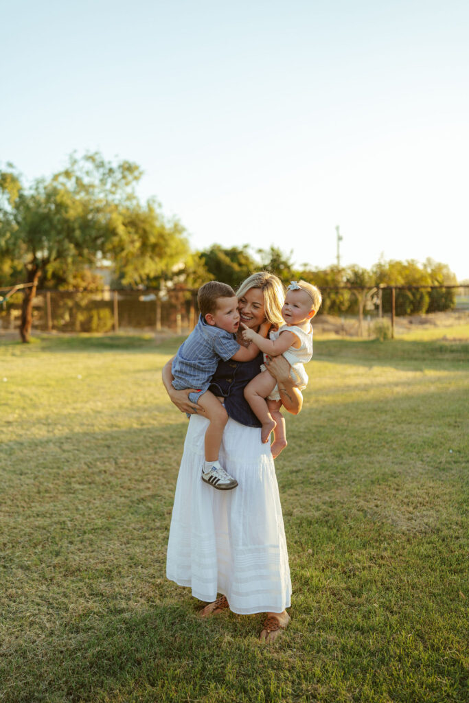 Mother cuddling her son and daughter during a natural outdoor family session with beautiful evening light in Gilbert, Arizona.