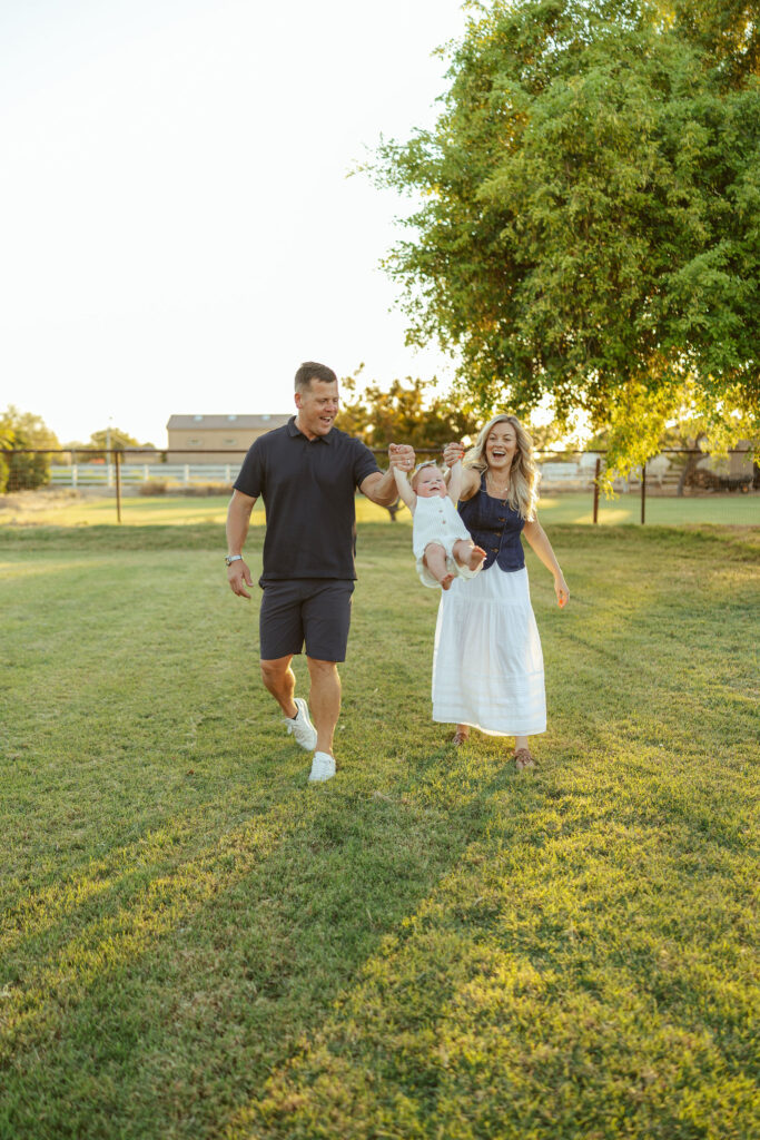 Family walking together across a lush green field during a relaxed outdoor family session with a Gilbert family photographer.