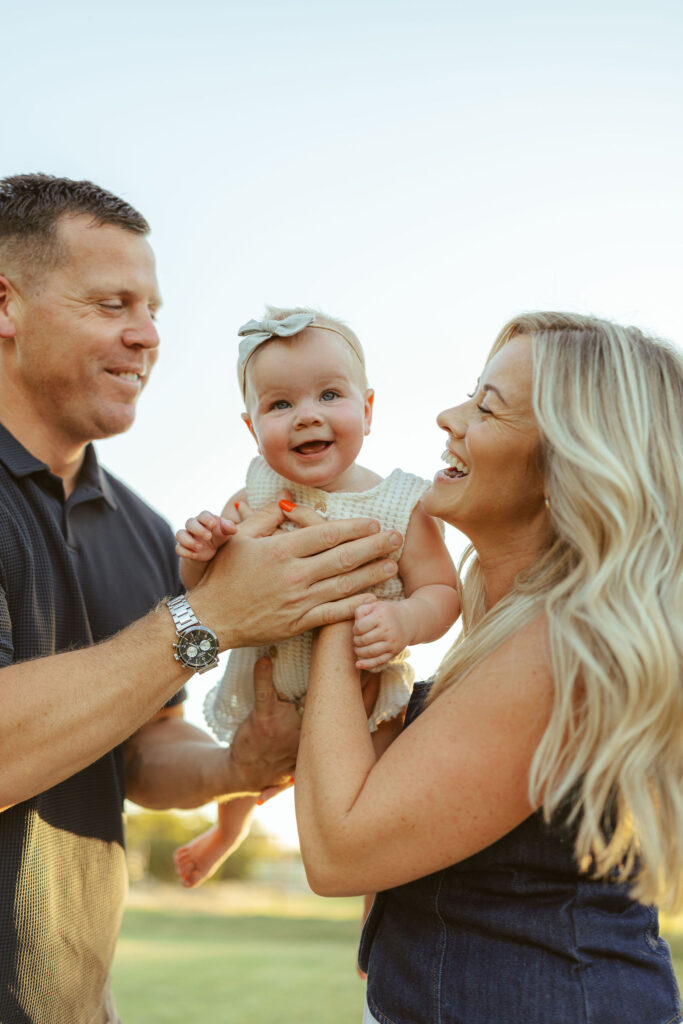 Happy parents holding their smiling baby during a golden hour family session in Gilbert, Arizona.