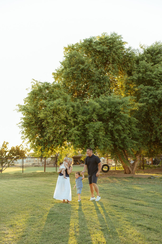 Family standing together beneath a large shade tree during a sunset family photography session in Gilbert, Arizona.