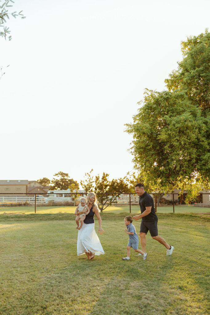 Parents walking with their children across a green field during a relaxed Gilbert family photography session.