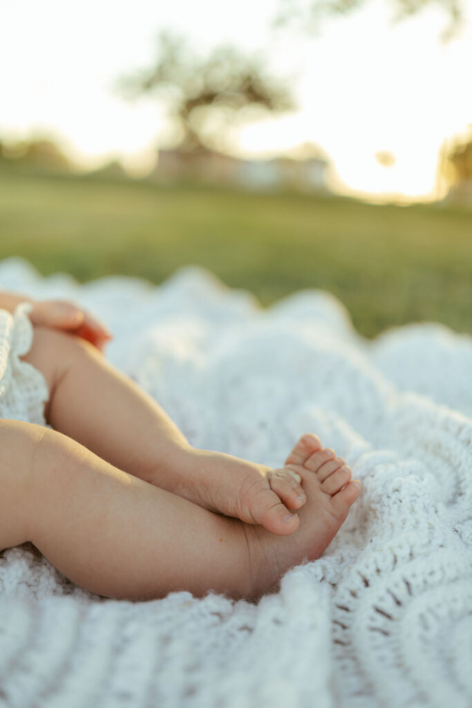 Close-up of a baby's tiny feet resting on a soft knit blanket during a Gilbert family photo session.