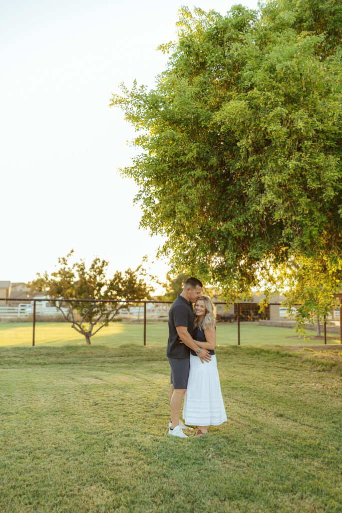 Parents embracing beneath a beautiful tree during a sunset family photography session in Gilbert.