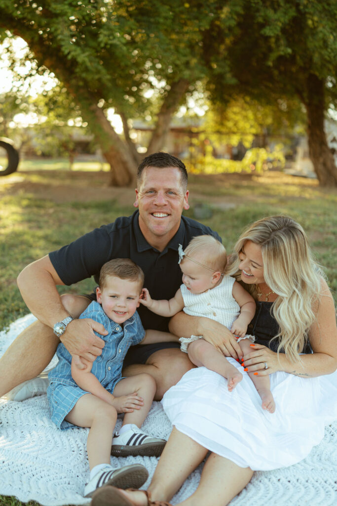 Happy family cuddling together on a blanket during a relaxed lifestyle family photography session in Gilbert.