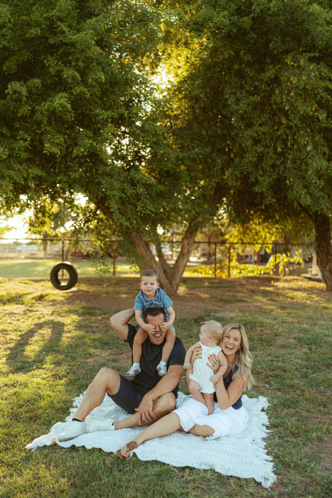 Parents smiling with their two young children during an outdoor family photography session in Gilbert, Arizona.