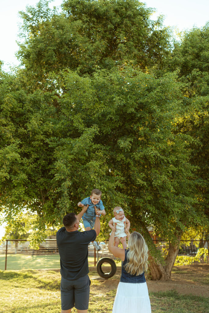 Father lifting his son onto his shoulders while mom holds their daughter during a family session in Gilbert, Arizona.