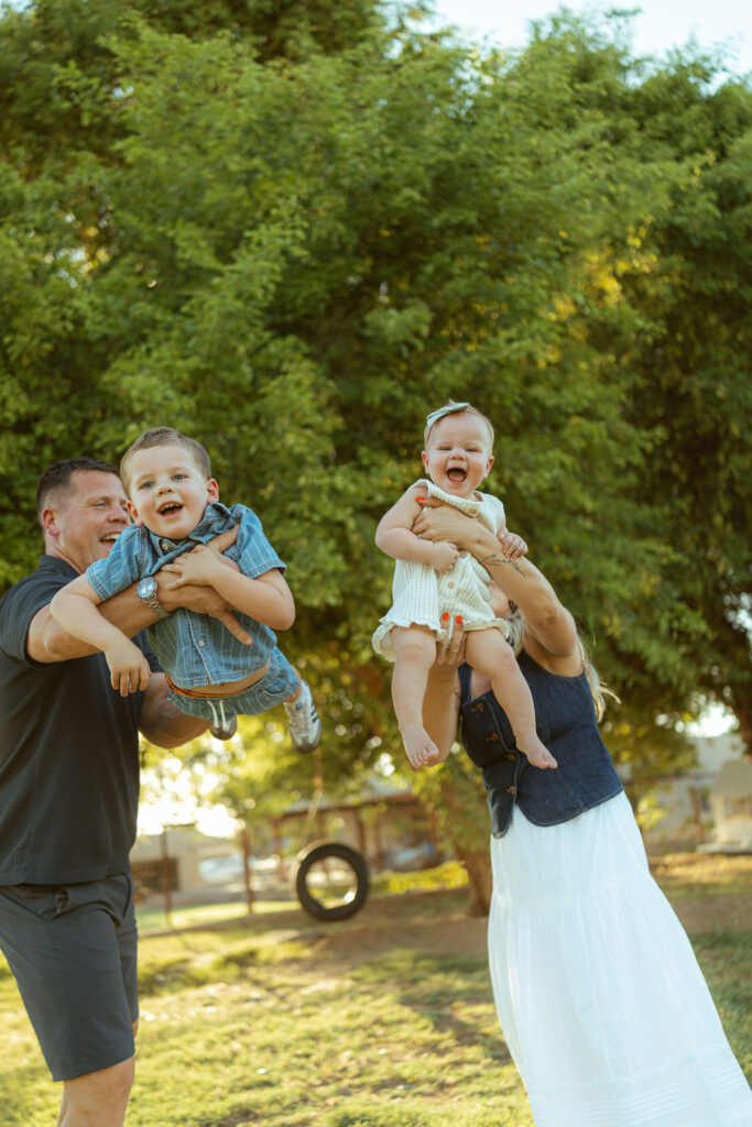 Parents lifting their young children into the air during a playful golden hour family photo session in Gilbert.