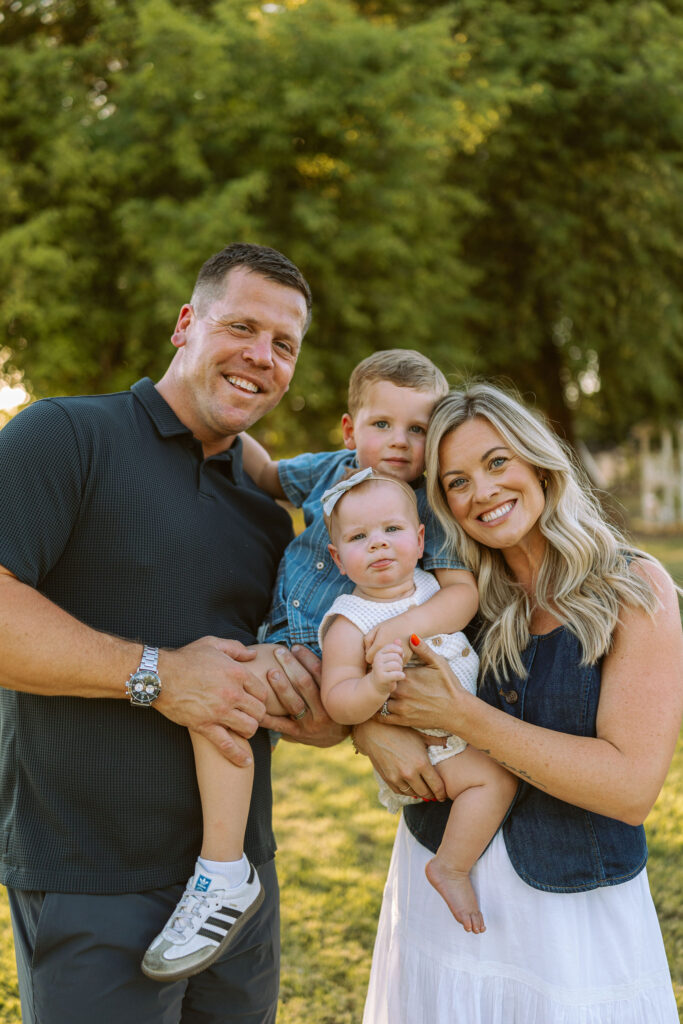Smiling family portrait with parents and two young children during a golden hour family photography session in Gilbert.