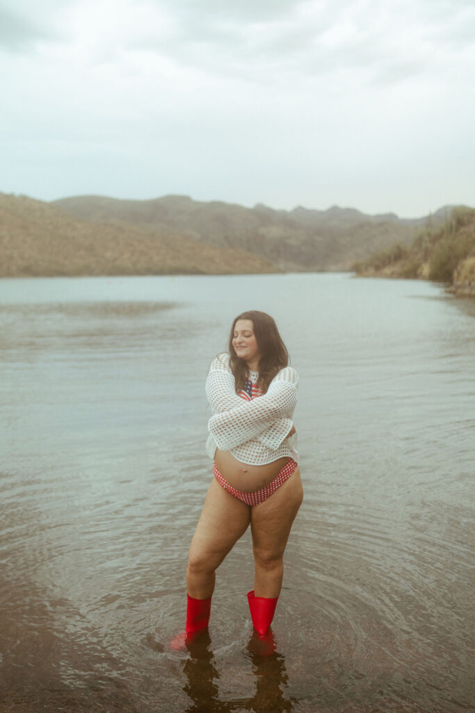 Expecting mother laughing while standing in the water during a summer maternity photography session at Butcher Jones Beach.