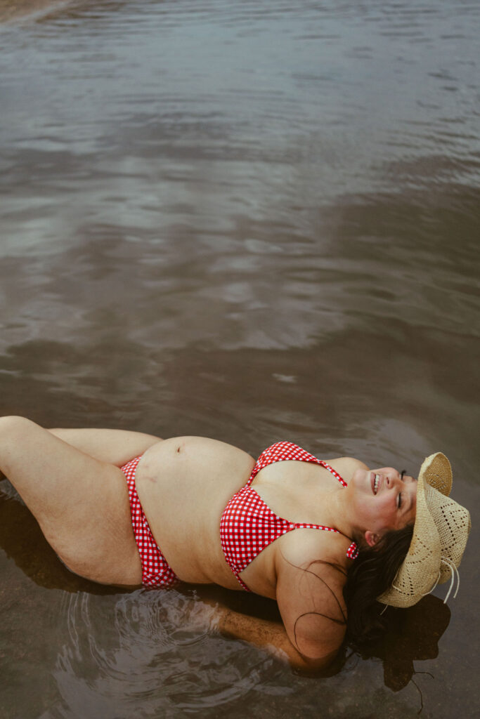 Expecting mother floating peacefully in the shallow water during a creative maternity photography session in Mesa, Arizona.