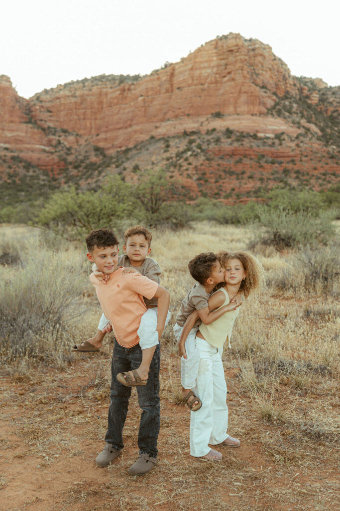 Sedona family photos featuring four siblings smiling together with their parents against Arizona's stunning red rock landscape.