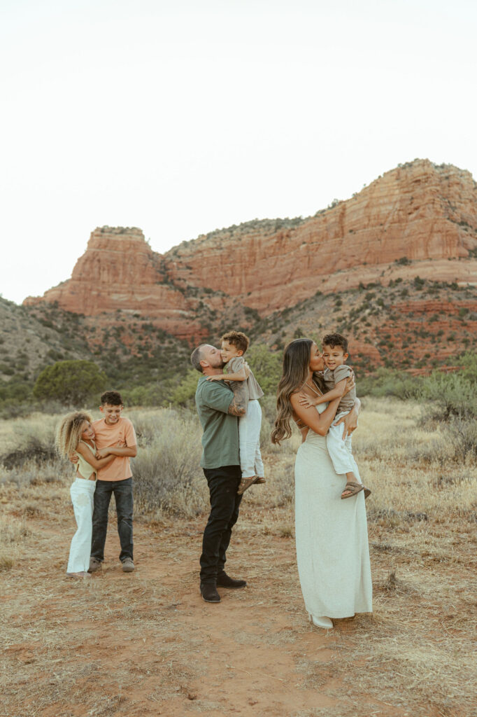 Candid family photography in Sedona as parents play with their children surrounded by the famous red rocks during sunset.