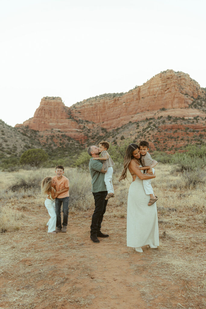 Father lifting his son while mom cuddles their youngest child during a natural family photography session in Sedona.