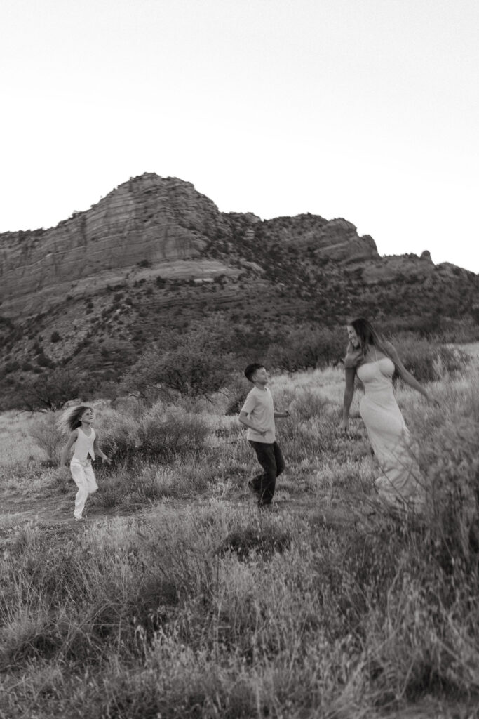 Black and white family photo in Sedona showing parents walking hand in hand with their children through the desert landscape.