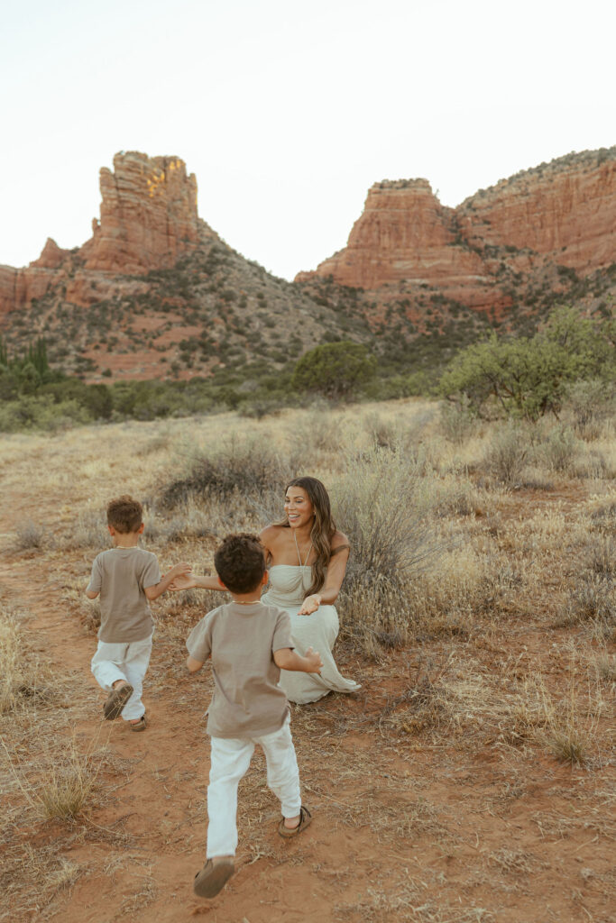 Children running toward their mother during a playful family vacation photography session in Sedona's beautiful desert landscape.